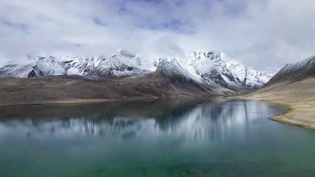 Drone view of beautiful snow covered mountains and peaceful lake, Ama Drime Snow Mountain and Dingjie Zongcuo Lake in Dingjie, Shigatse, Tibet, China. Travel concept 4k real time footage aerial view.