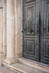 Obraz premium Traditional Weathered Wooden Doors Beside A Historic Stone Column In Venice Italy Architecture