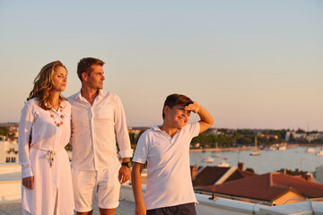 Obraz premium Family on Rooftop Terrace Overlooking Seaside Harbor at Sunset in Umag, Croatia