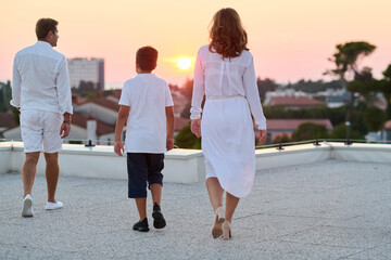 Obraz premium Family Walking on Rooftop Terrace at Sunset With Sea View and Relaxed Evening Mood