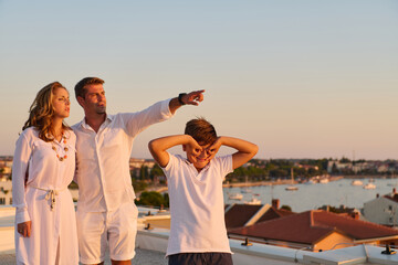 Obraz premium Family on Rooftop Balcony With Sea View at Sunset Enjoying Summer Vacation Together