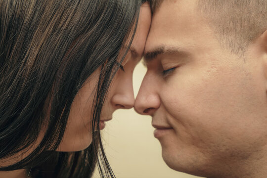 Close-up of a loving couple gently touching foreheads, conveying intimacy and connection in a warm, soft-focused atmosphere.