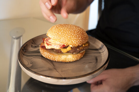 Close-up of a delicious sesame seed hamburger on a stylish plate, showcasing juicy meat, melted cheese, and fresh toppings, perfect for food lovers.