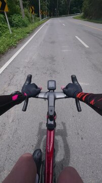 First-person point of view of a road cyclist approaching a sharp winding curve on a scenic mountain road surrounded by lush tropical forest. The immersive footage showcases endurance cycling, outdoor 