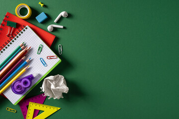 Naklejka premium Back to school flatlay with colorful school supplies, pencils, notebook and rulers on green background