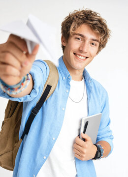 Smiling young male student throwing a paper airplane isolated on white background