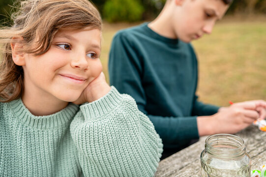 Smiling girl while brother painting during outdoor creative activity