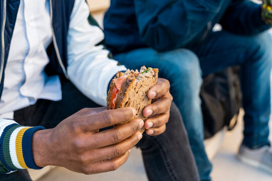 Close-up of two men sitting on stairs having lunch break