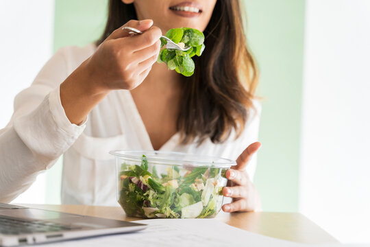 Crop view of young architect eating mixed salad at desk