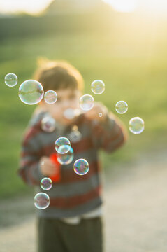 Blowing soap bubbles outdoors in summer sunlight with selective focus