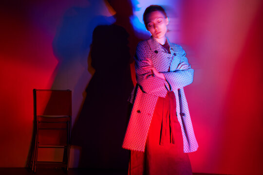 Woman wears a tweed jacket under red neon light indoors