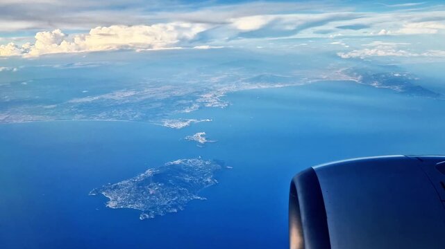 The islands of Procida and Ischia seen against the backdrop of the blue sky by an airplane passenger through the window