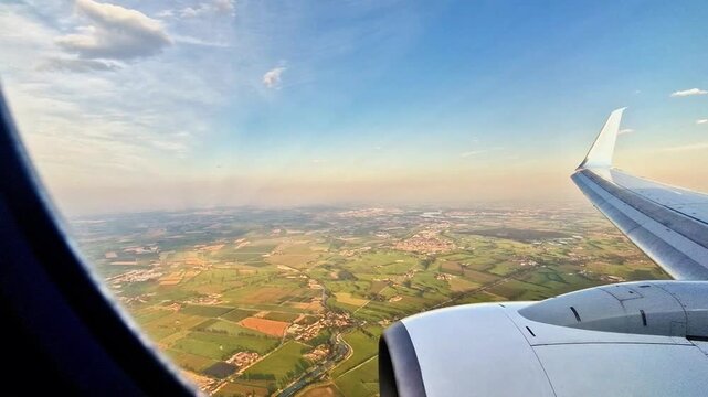 The wonderful panorama of the blue sky with white clouds and the ground below as seen by an airplane passenger through the window