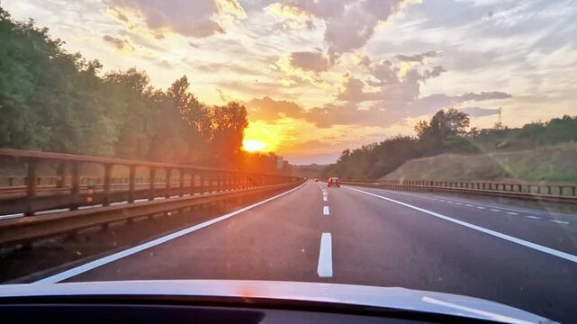 Driving a POV car with sunset on the horizon during a summer evening along an Italian highway. The video was shot along the A22, Autrostrada del Brennero, in Italy