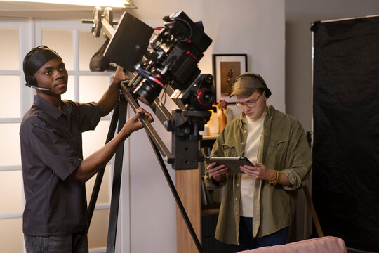 Film crew operates a camera crane during an indoor movie production