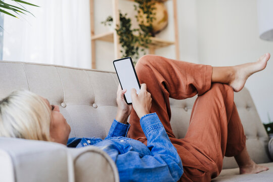 Woman using smart phone on sofa at home