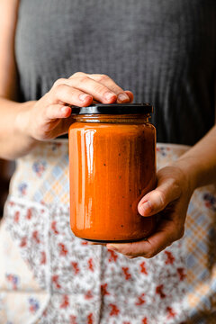 Hands of mature woman holding homemade tomato sauce jar