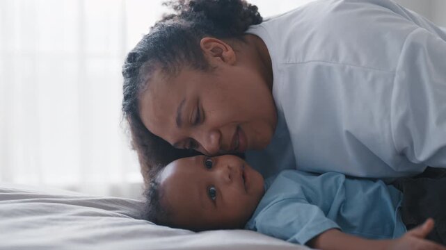 African american woman playing with baby in cozy home interior, family moments. Little son or daughter looking at mother and smiling, happy childhood and motherhood, unconditional love and tenderness