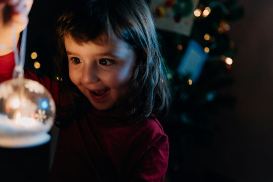 Portrait of excited little girl holding lighted glass ball at Christmas time