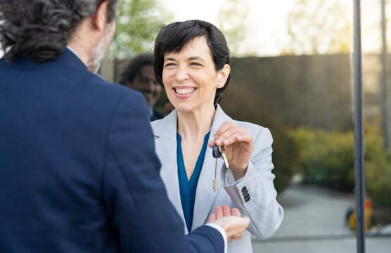 Smiling businesswoman with house key looking at real estate agent