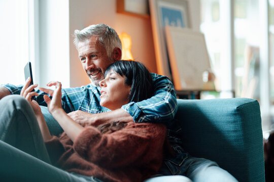 Heterosexual couple using mobile phone in living room