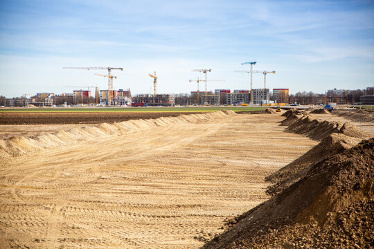 Germany, Bavaria, Munich, Sandy area prepared for construction site with industrial cranes in background