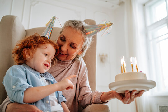Senior woman with grandson holding birthday cake at home