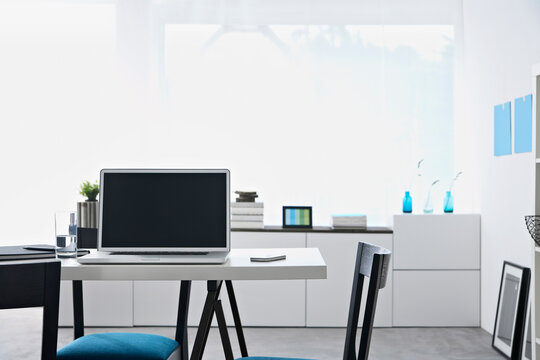 Modern empty home office workspace with laptop on desk indoors