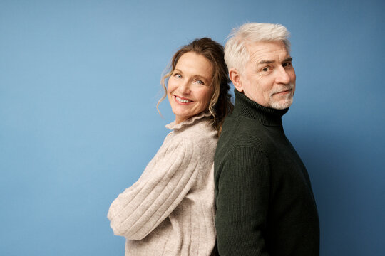 Mature man and woman standing back to back against blue background