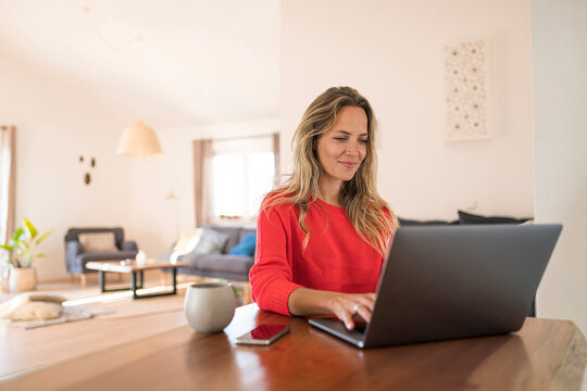 Woman using laptop on dining table at home
