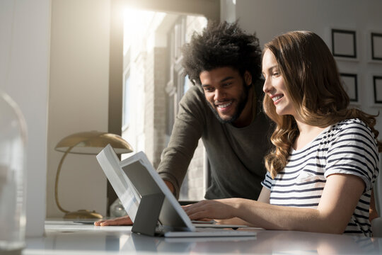 Smiling couple working at home with laptop and tablet