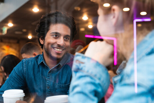 Portrait of smiling young man in a coffee shop looking at young woman
