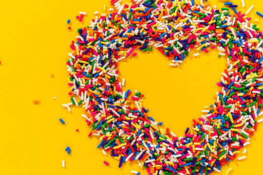 Colorful candy heart shape on yellow surface