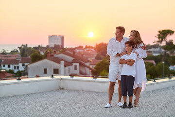 Obraz premium Family on Rooftop Balcony at Sunset With Sea View Over Coastal Town