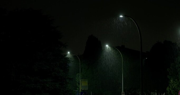 Rain Falls Beneath Glowing Streetlights During a Night Thunderstorm in Bassano del Grappa, Italy - Handheld Shot