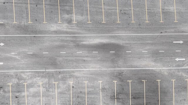 Empty parking lot under cloudy skies. Gray asphalt shows faded white lines