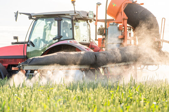 Farmer in tractor spraying crops at sunset