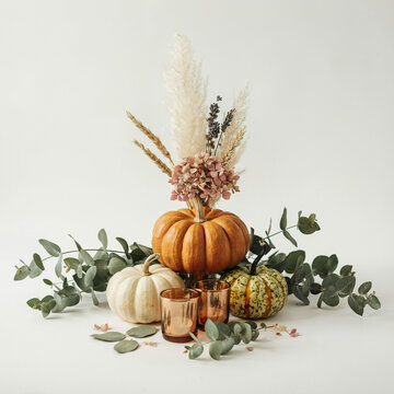Boho autumn pumpkin centerpiece with pampas grass and eucalyptus, rustic fall floral arrangement, elegant thanksgiving table decor on white background