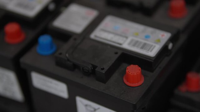 Car batteries with red and blue caps. Still shot emphasizes industrial automotive components. Ideal for automotive, energy