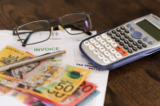 EOFY tax time concept with Australian banknotes and invoices beside calculator and glasses