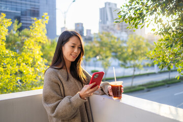 Obraz premium Woman looking at smartphone with iced coffee