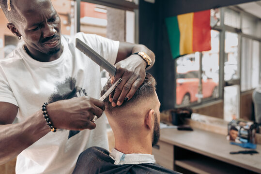 African american barber cutting man's hair in barbershop