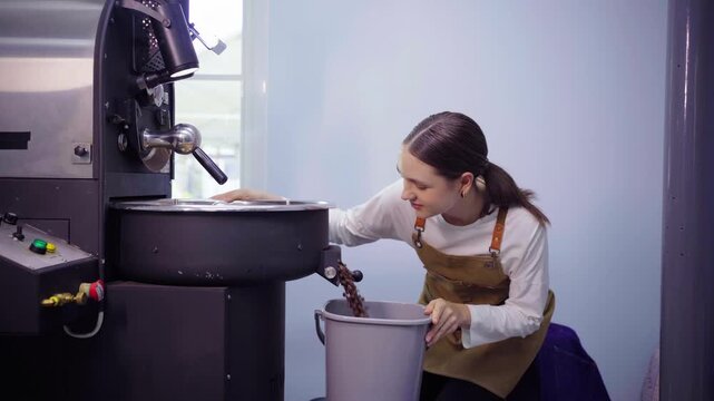 Female coffee roaster discharging fresh roasted beans into bucket