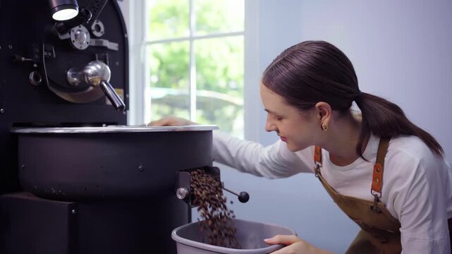 Female coffee roaster discharging fresh roasted beans into bucket