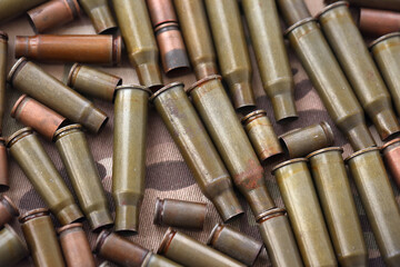 Fototapeta premium Big amount of shells cartridges from assault rifle bullets on old camouflage fabric