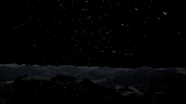 Snow is falling against the backdrop of mountains and a black background