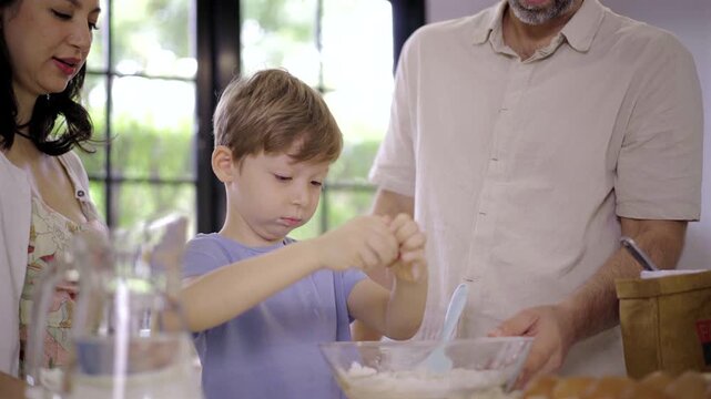 Young boy cracking egg into flour bowl for baking in kitchen