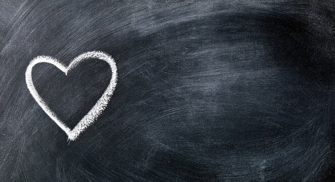 A white chalk heart outlined on a dark, textured blackboard