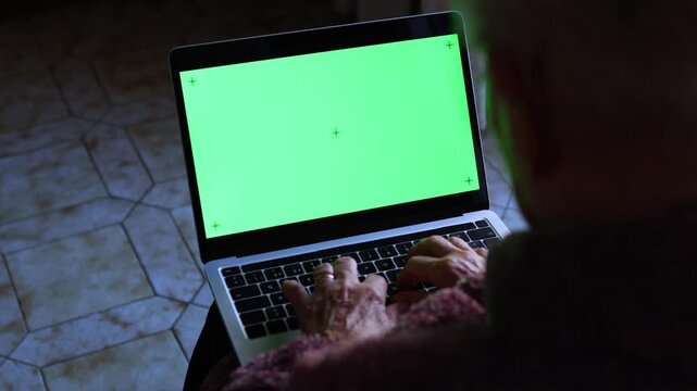 Elderly woman using laptop screen with a chroma key background