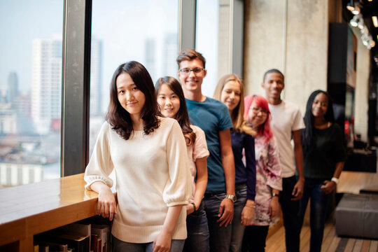 Diverse group of young adults smiling in a modern office setting.